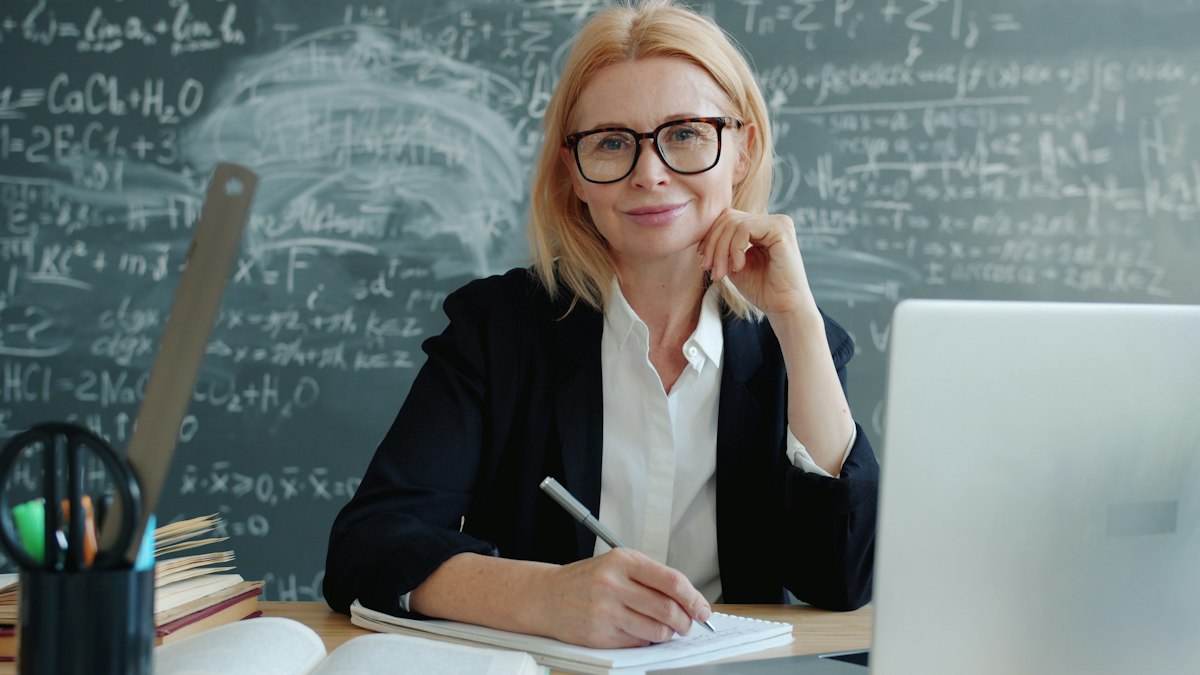 Professora sorrindo enquanto dá aula online pelo laptop